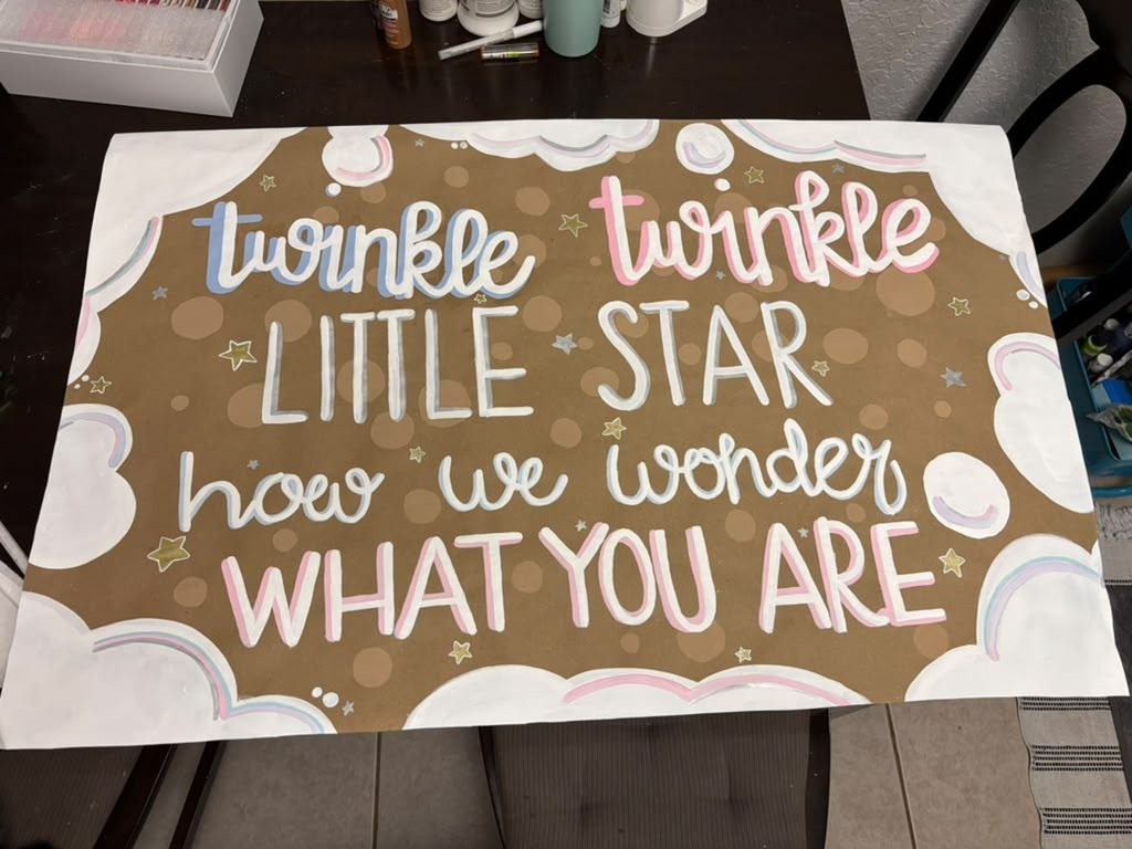 Hand-painted kraft paper banner reading "twinkle twinkle little star, how we wonder what you are" with clouds, rainbows and gold stars