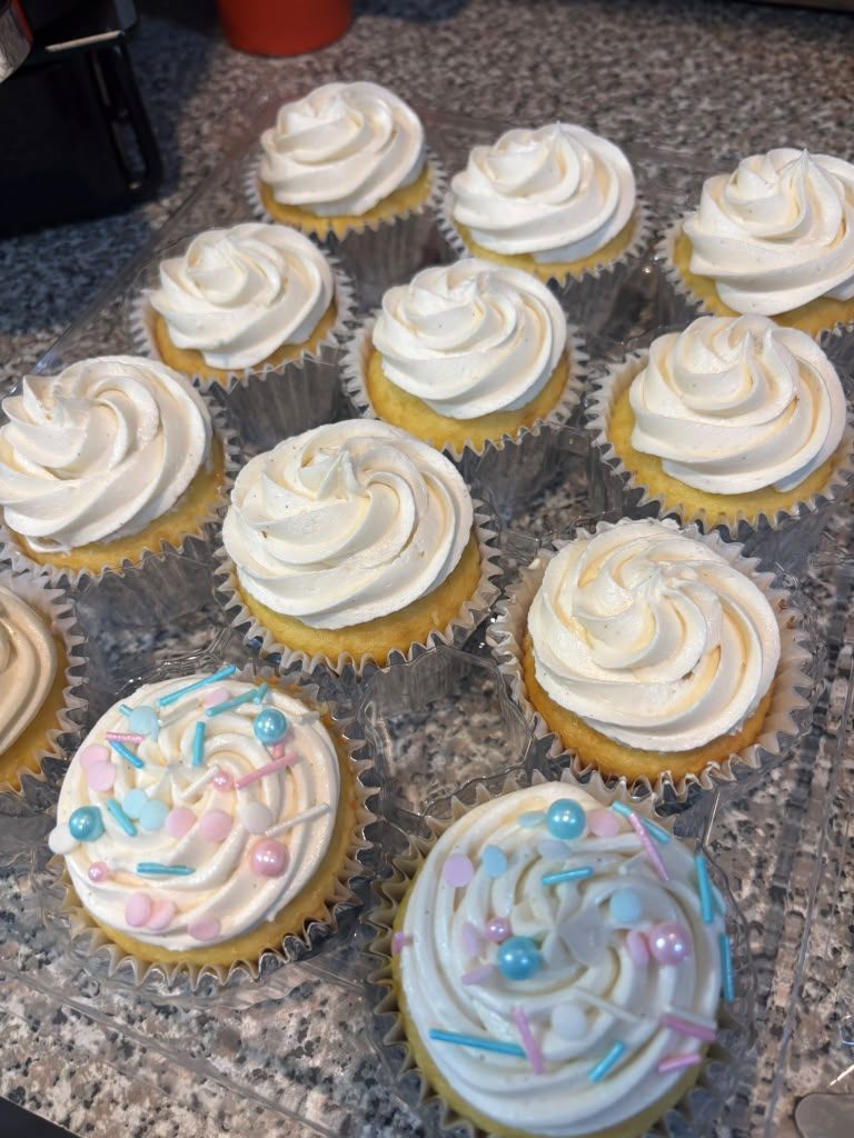 Tray of frosted vanilla cupcakes decorated with silver and black sprinkles for a gender reveal party