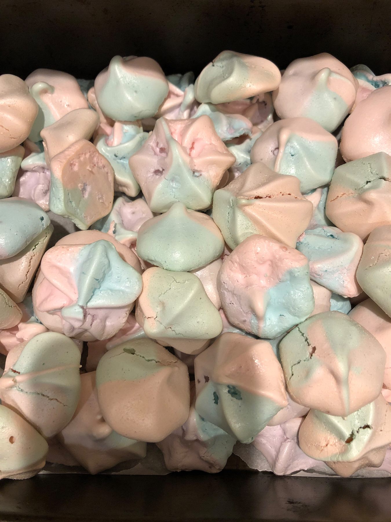 Tray of pastel meringue kisses swirled in pink, blue and cream